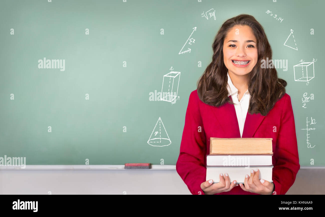 College Bound. Pretty ethnic or Hispanic teen with braces, wearing a red school uniform blazer in front of green chalkboard. Isolated on blackboard wi Stock Photo