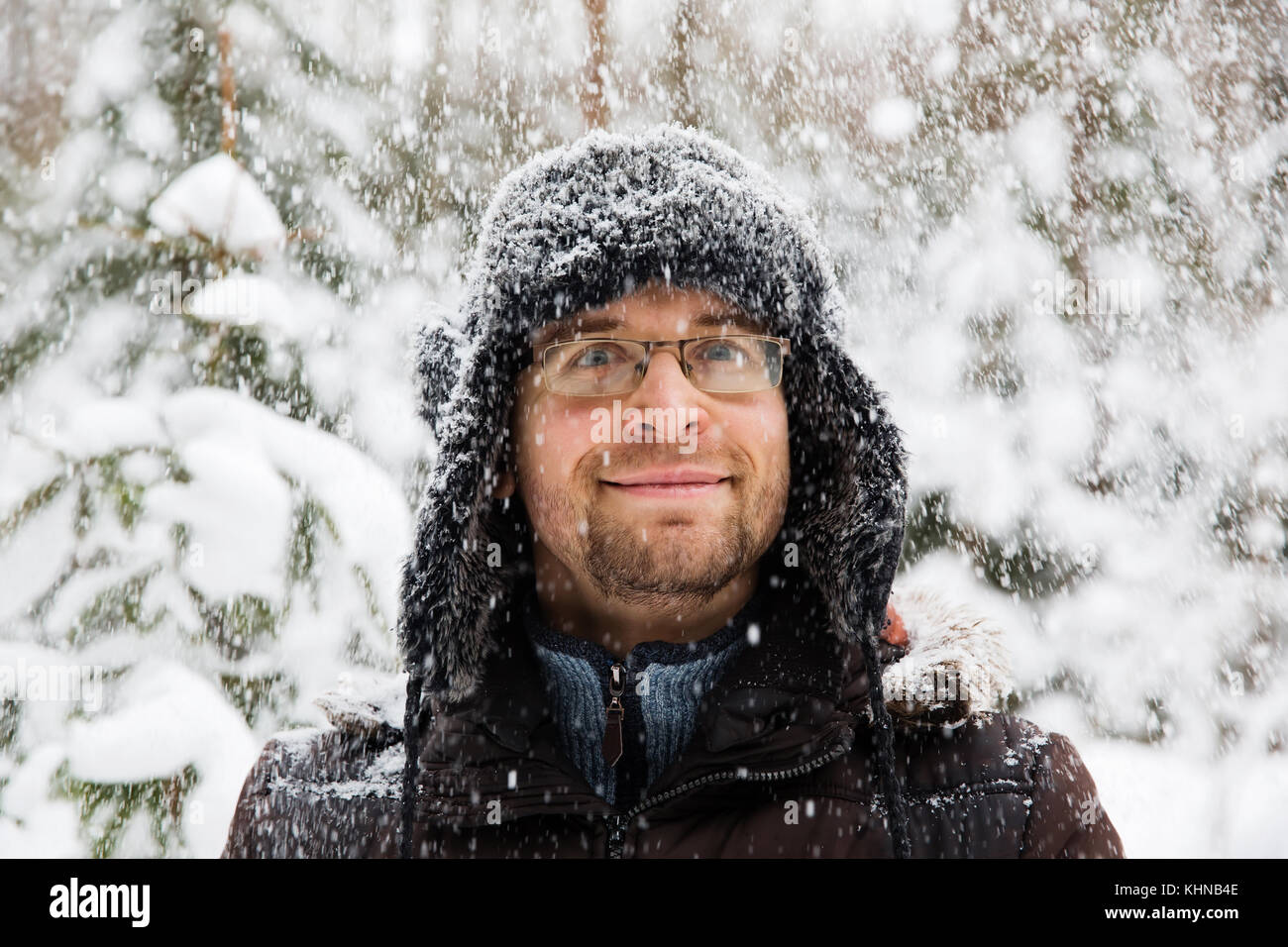 Man in fur winter hat with ear flaps smiling portrait. Extreme in the forest Stock Photo