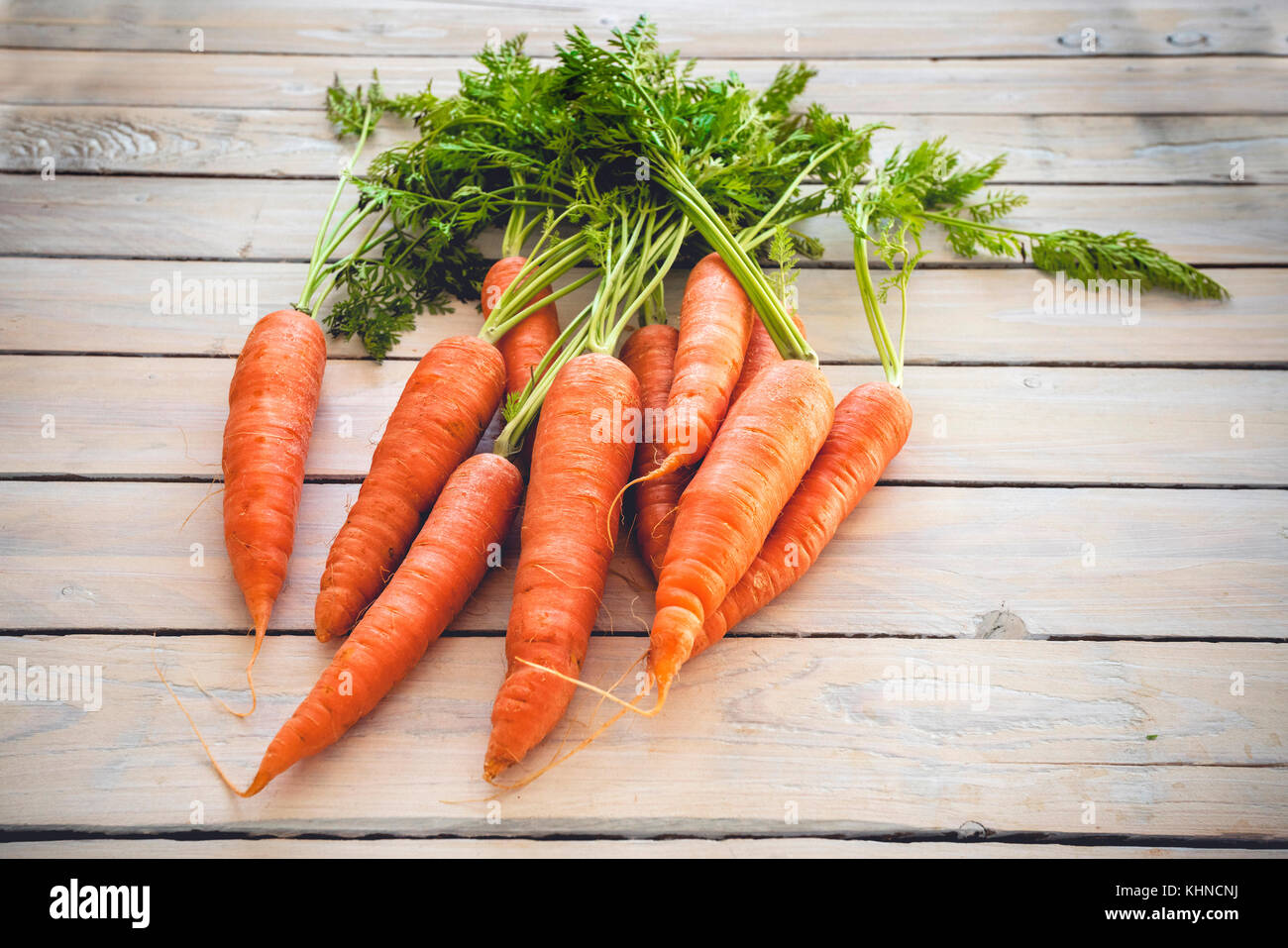 Raw carrots with green plants on a wooden table Stock Photo