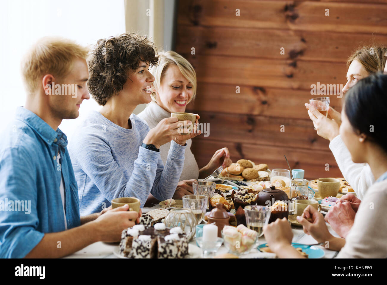 Several friends having tea with homemade pastry by festive table and ...