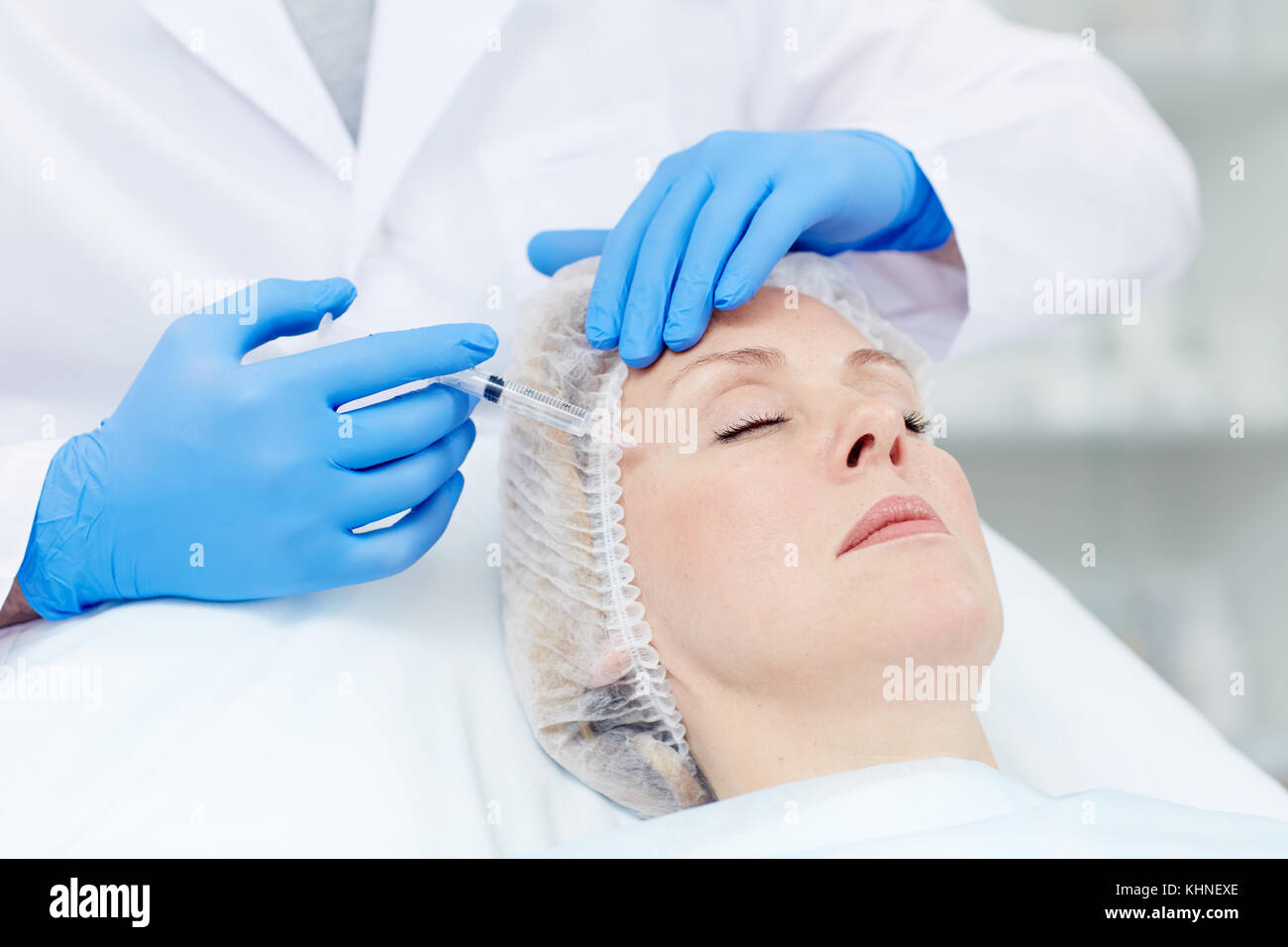 Plastic surgeon making botox injection in temple of his aging patient Stock Photo