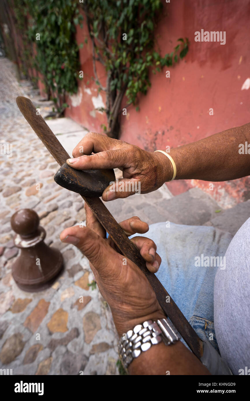closeup of a mans hands sharpening a machete in mexico with a grinding