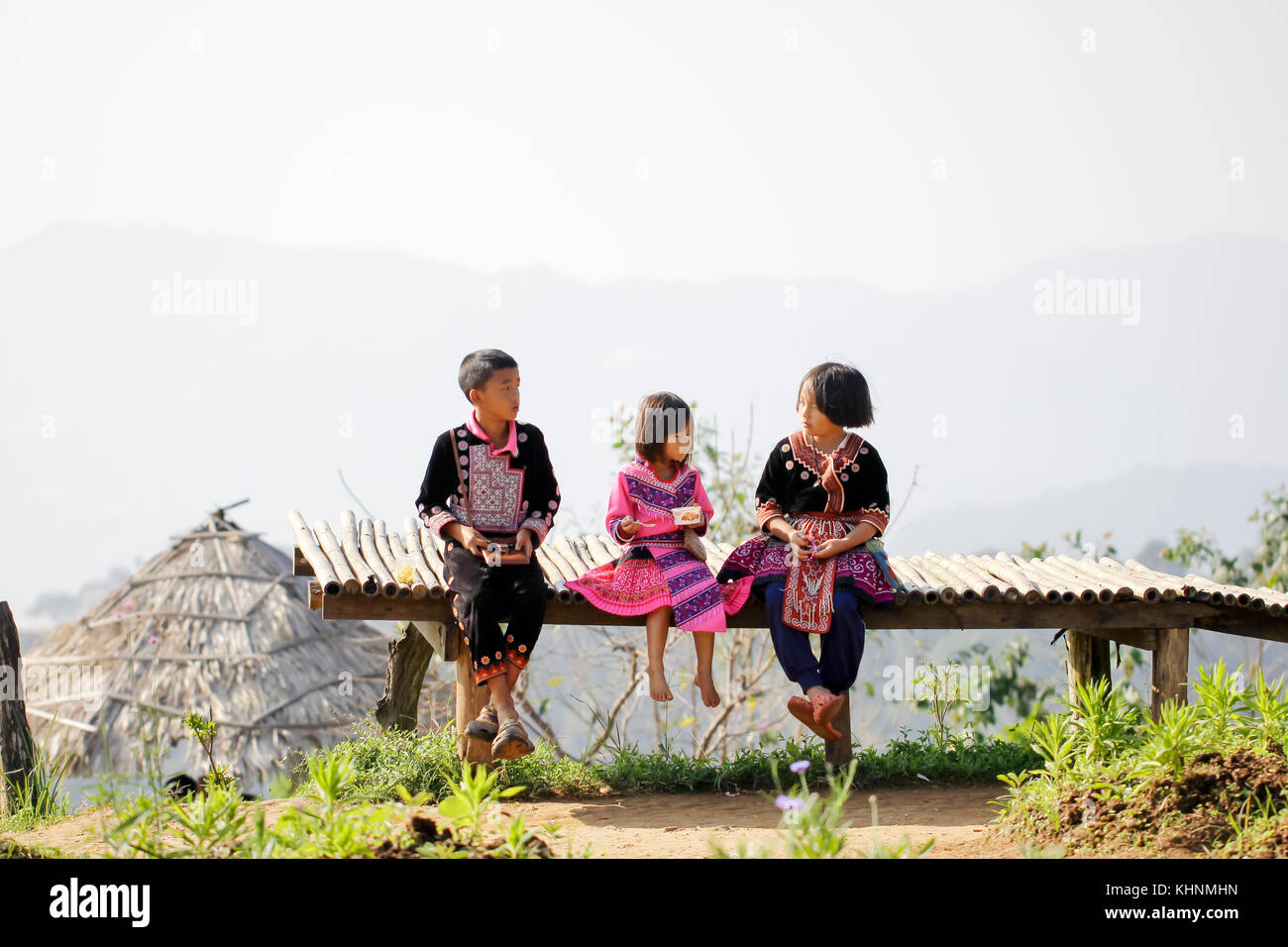Lovely boy and girl playing outdoors while posing wearing ethnic clothes from the Hmong tribe, indigenous people of Thailand. Stock Photo