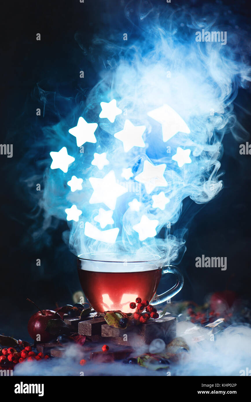 Cup of tea with dense steam and shining stars in conceptual astronomy scene. Dark food photography with smoke. Stock Photo