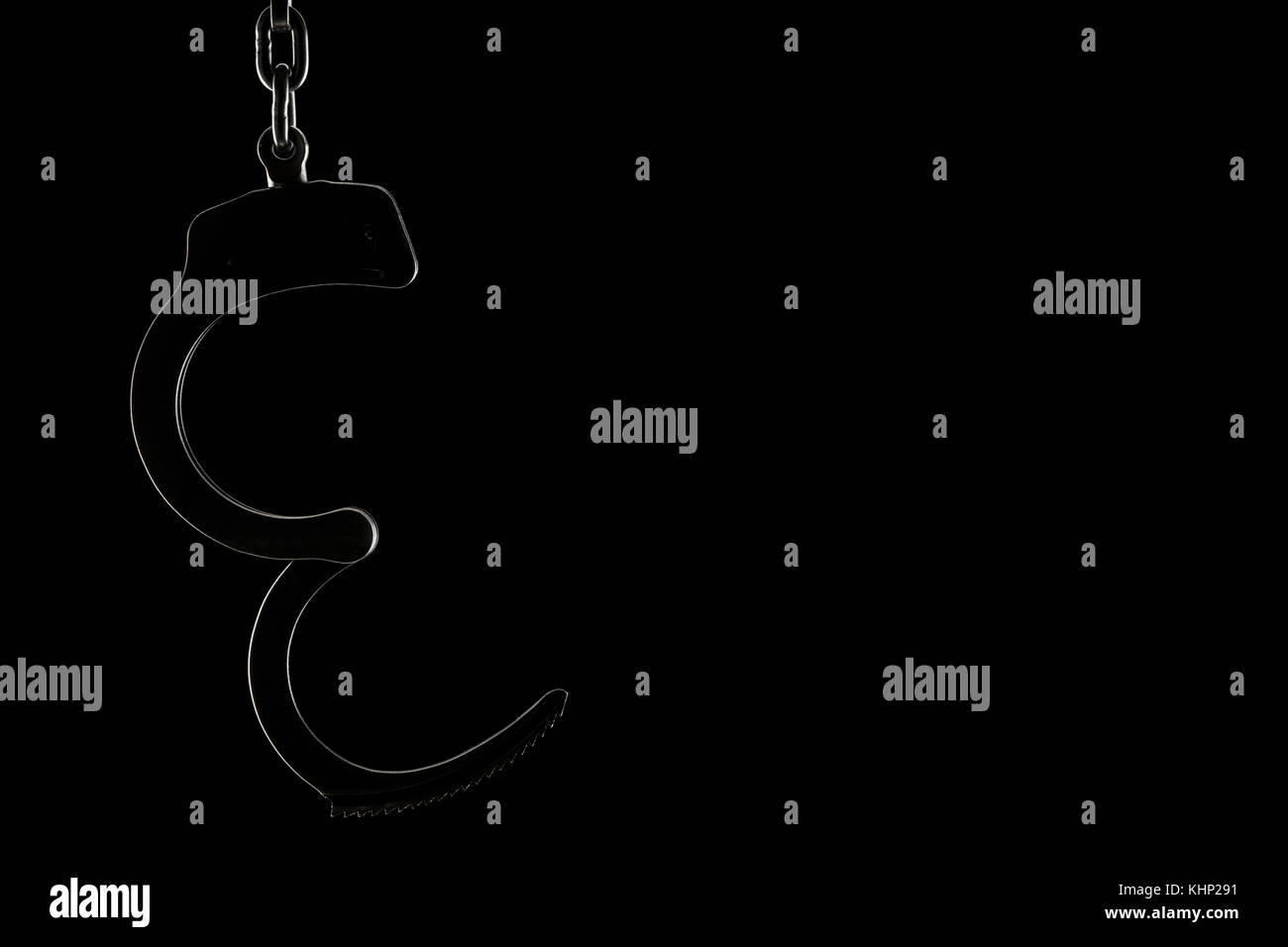 Rim lit unlocked handcuffs silhouette on a black background with copy space Stock Photo