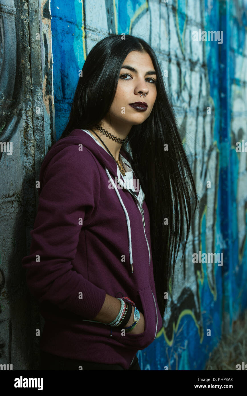 A grunge styled and dark haired woman with a hooded purple sweatshirt Stock Photo