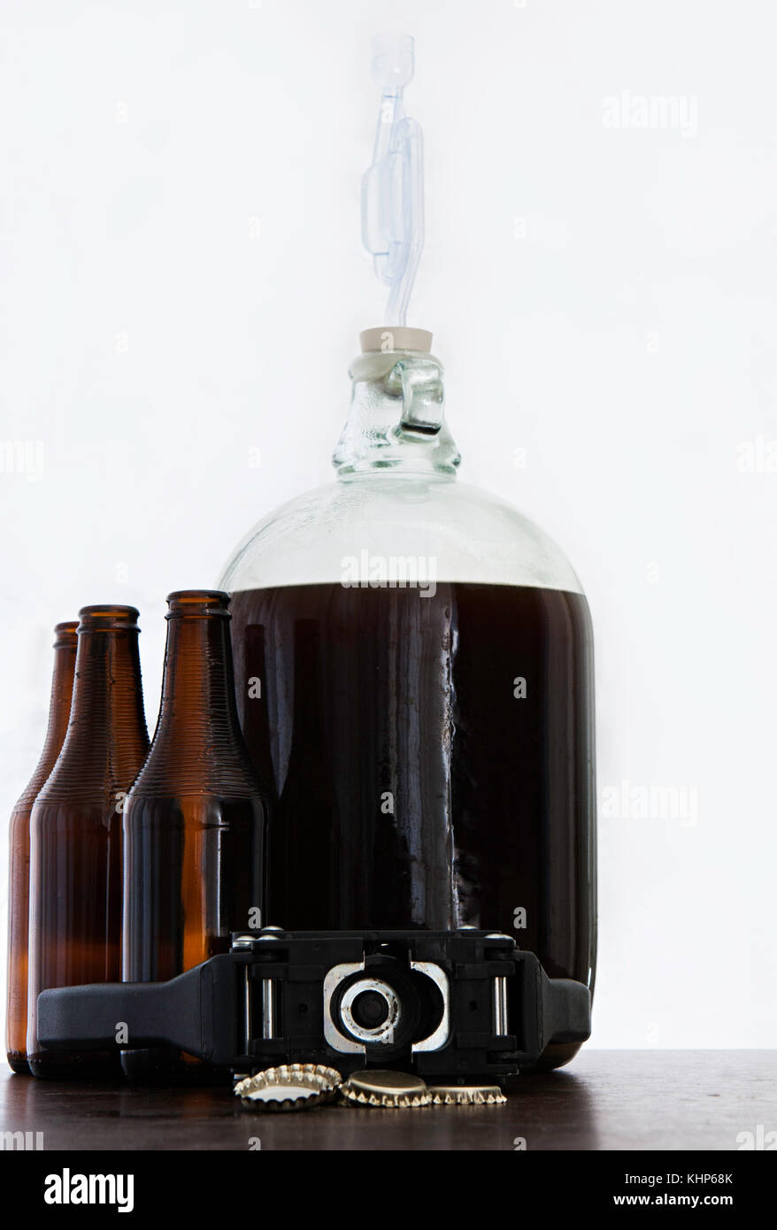 Fermented beer in a demijohn with airlock and hand capper with dark
