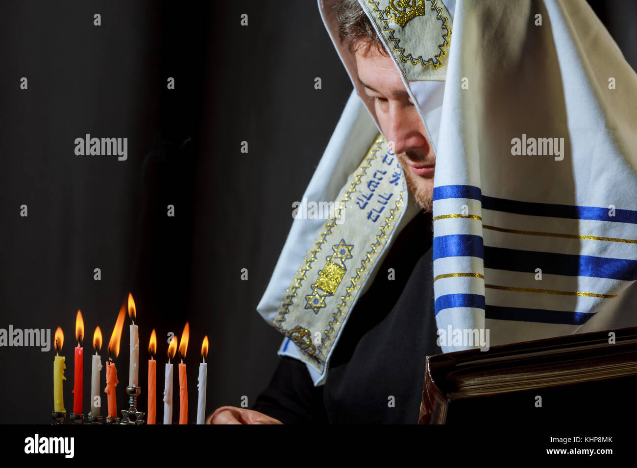 Jewish candle lights male hand lighting candles in menorah on table