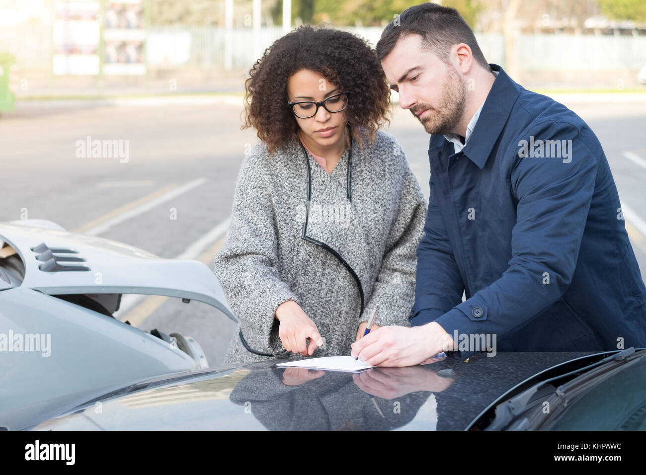Man and woman filling an insurance car form after bad car crash Stock