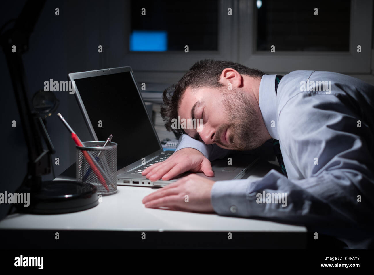Office worker sleeping on the computer keyboard at night in the office Stock Photo