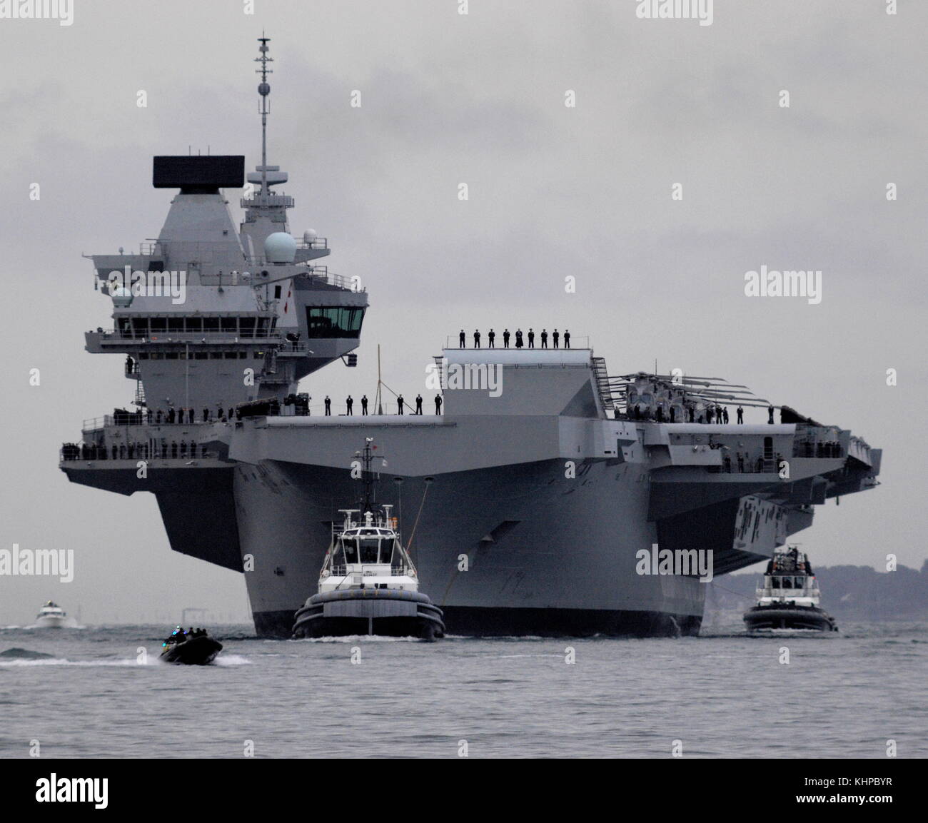 AJAXNETPHOTO. 16TH AUGUST, 2017. PORTSMOUTH, ENGLAND. - ROYAL NAVY'S BIGGEST WARSHIP SAILS INTO HOME PORT - HMS QUEEN ELIZABTH, THE FIRST OF TWO 65,000 TONNE, 900 FT LONG, STATE-OF-THE-ART AIRCRAFT CARRIERS SAILED INTO PORTSMOUTH NAVAL BASE IN THE EARLY HOURS OF THIS MORNING, GENTLY PUSHED AND SHOVED BY SIX TUGS INTO HER NEW BERTH ON PRINCESS ROYAL JETTY. THE £3BN CARRIER, THE LARGEST WARSHIP EVER BUILT FOR THE ROYAL NAVY, ARRIVED AT ARRIVED AT HER HOME PORT TWO DAYS AHEAD OF HER ORIGINAL SCHEDULE.  PHOTO: JONATHAN EASTLAND/AJAX  REF: D171608 6764 Stock Photo
