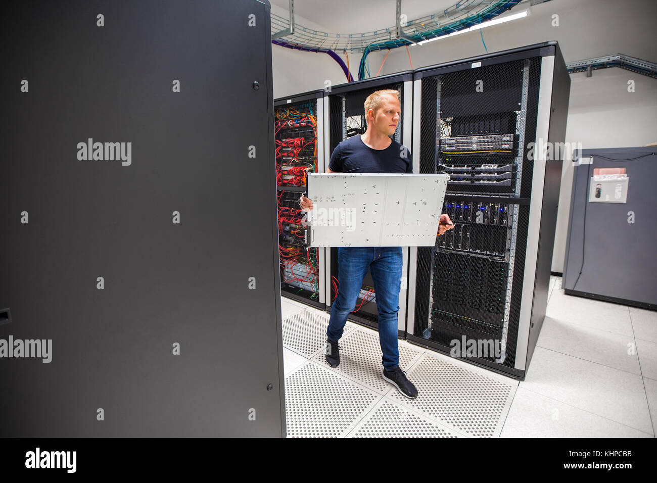 IT Consultant Carrying Blade Server While Walking In Datacenter Stock Photo