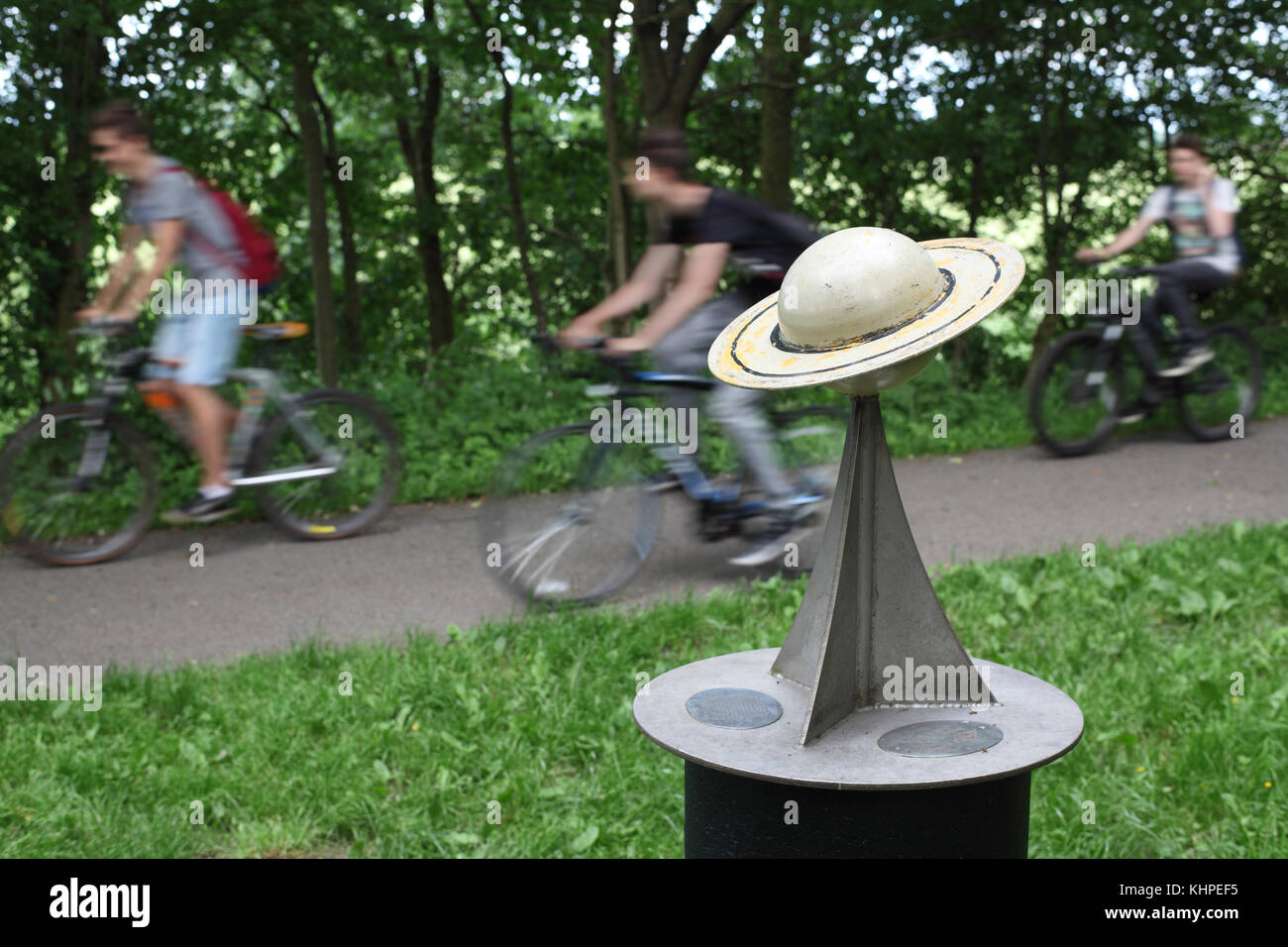Cyclists pass a model of the planet Saturn, on the York to Selby cycle path - the location of a 10.4 km scale model of the solar system. Stock Photo
