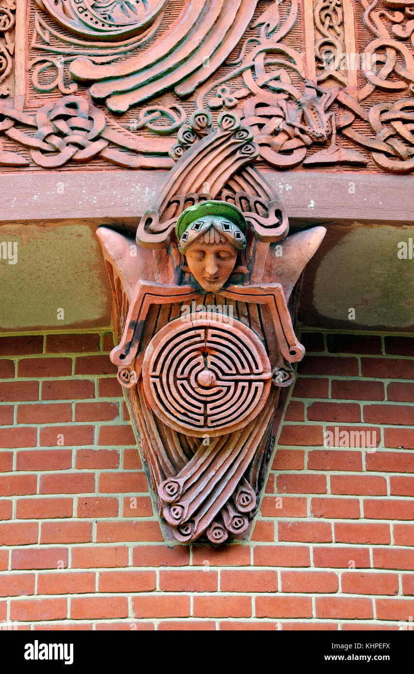 A corbel, comprising a figure holding a maze, supporting a frieze around the outside of the Watts Chapel, Compton, Surrey. Stock Photo
