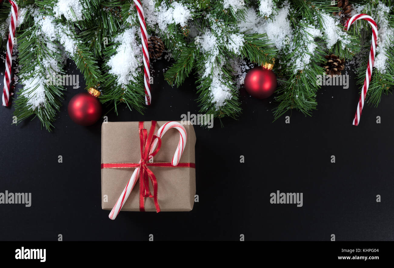 Christmas gift with snowy evergreen tree branches, candy canes and red ...