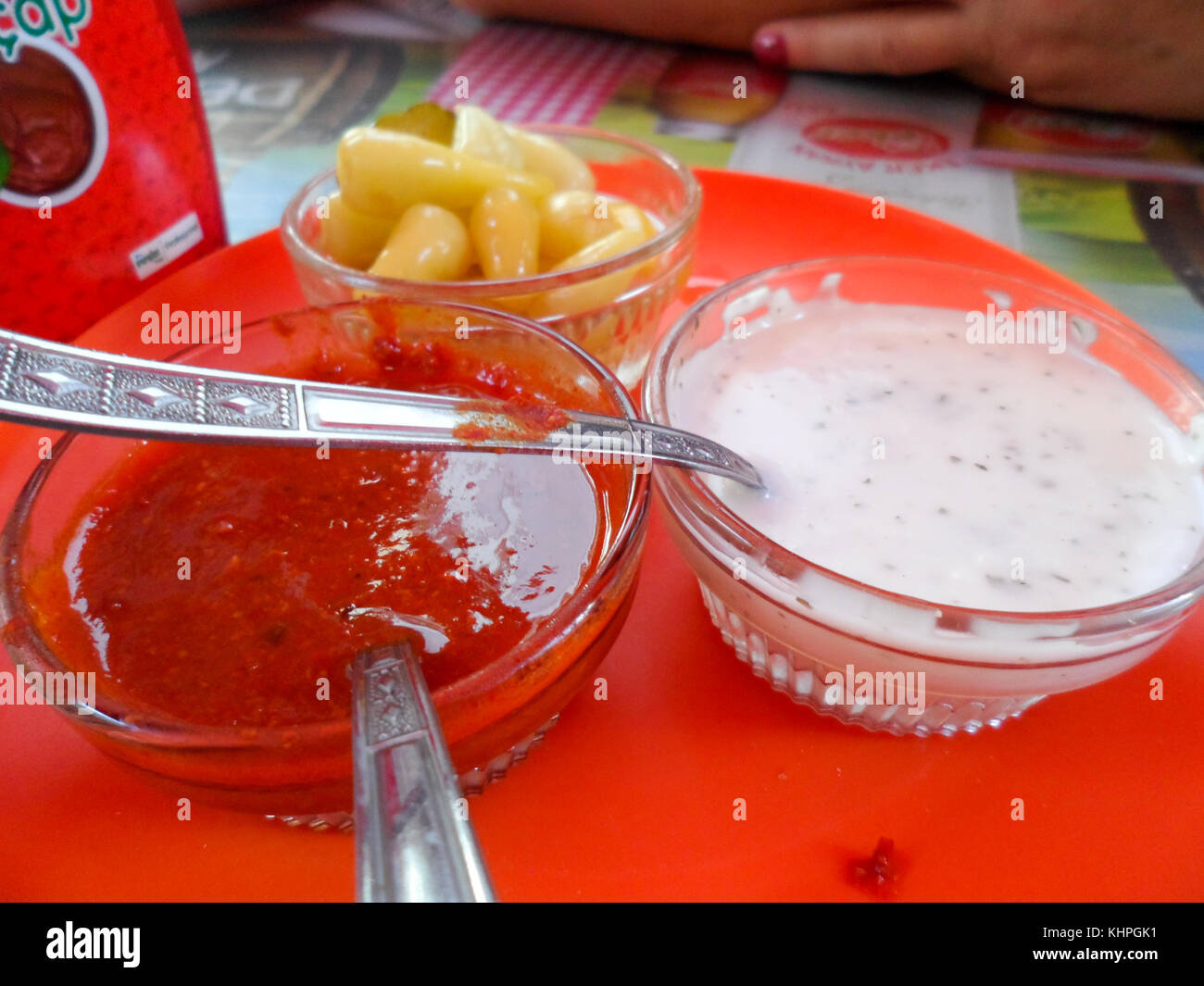 Condiment bowls of Chili sauce, Pickled Garlic cloves and Minted mayonnaise on a table in a Turkish Kebab shop, Marmaris, Turkey Stock Photo