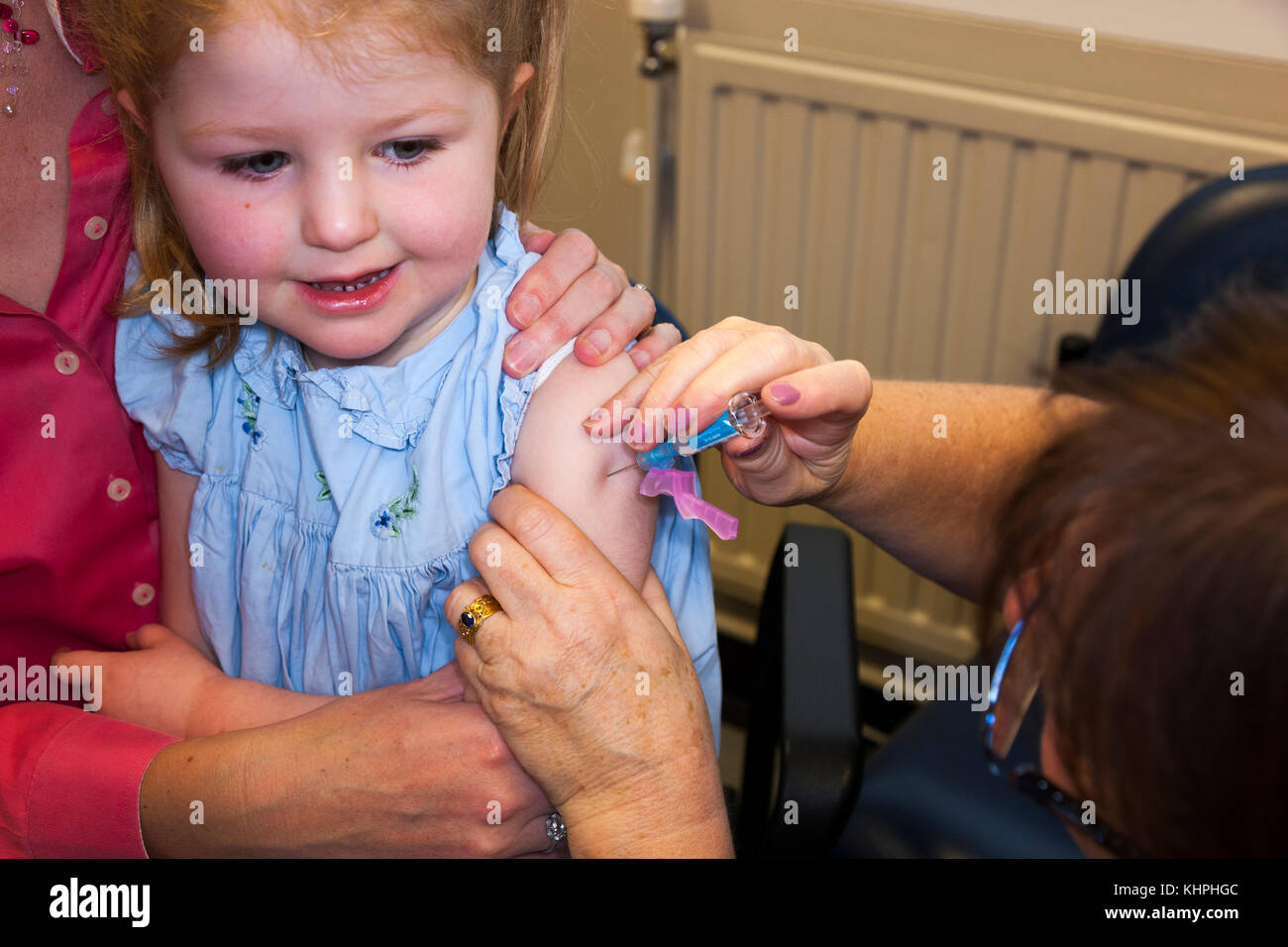 Practice nurse giving NHS 4-in-1 pre-school booster / Pre school booster & MMR second dose immunisation / inoculation / jab to 3 three year old child Stock Photo