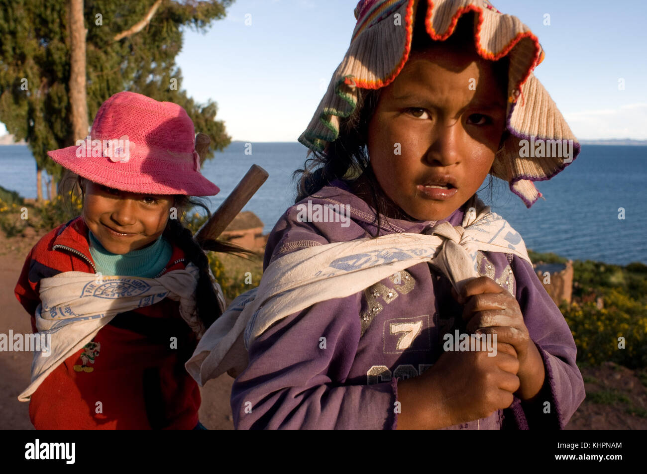 Some girls on the island of Amantaní dressed in their typical regional costume at the foot of Lake Titicaca. Amantani Island, Lake Titicaca, Puno, Per Stock Photo