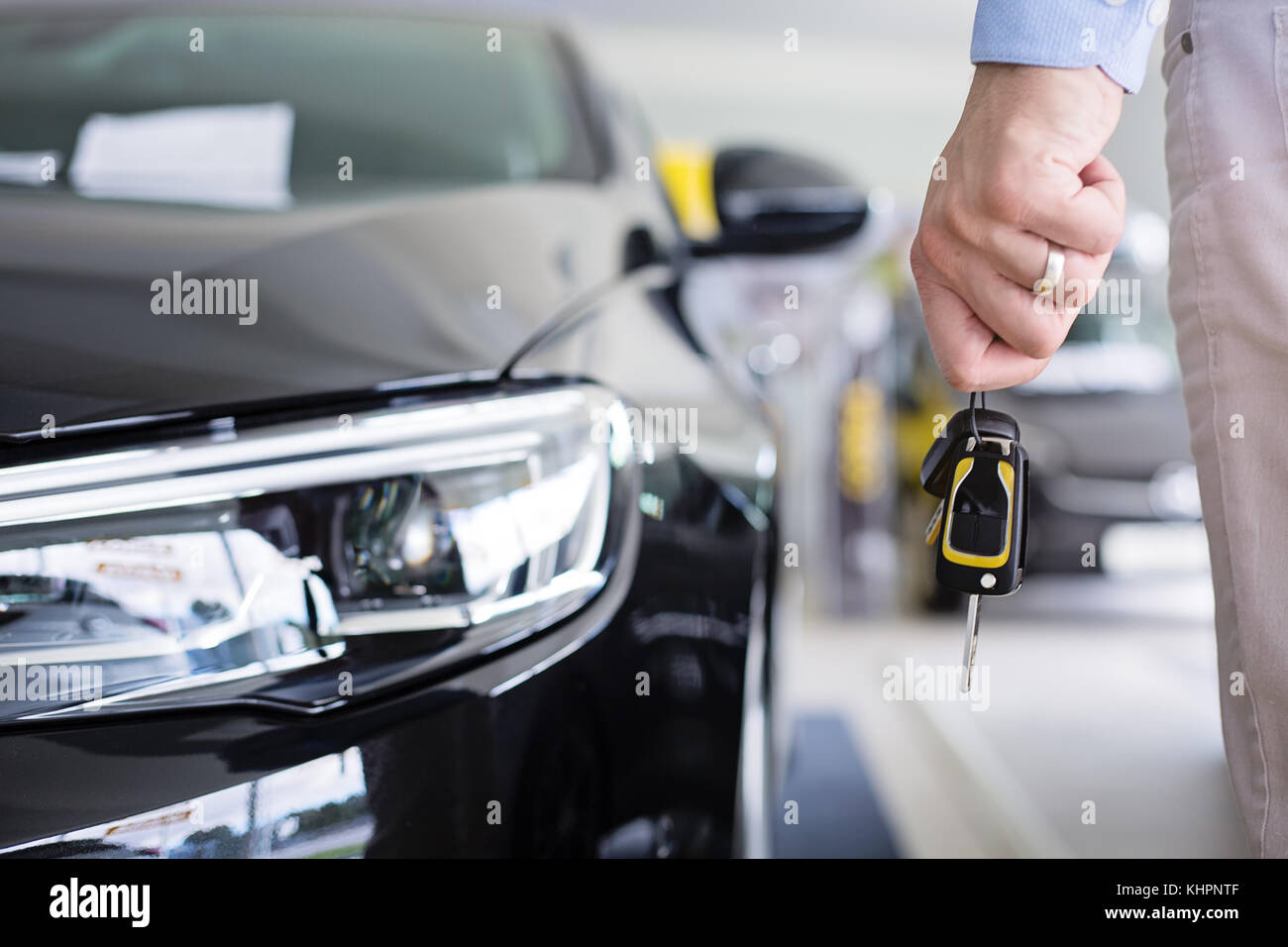 Close up photo of male hand holding a car keys next to a brand new ...