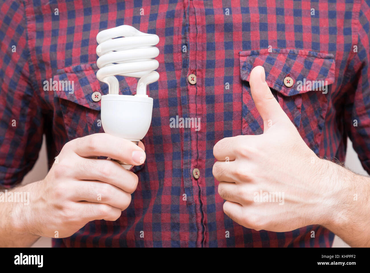 The man in the shirt is holding an energy-saving light bulb Stock Photo