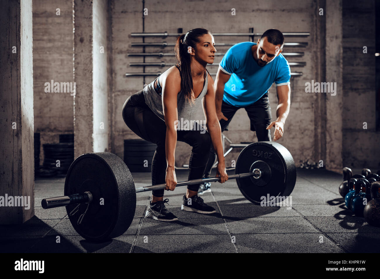 Young woman doing hard exercise at the gym with a personal trainer. Stock Photo