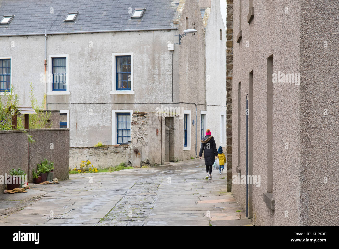 mother and young child walk up cobbled street in Stromness, Orkney, Scotland Stock Photo