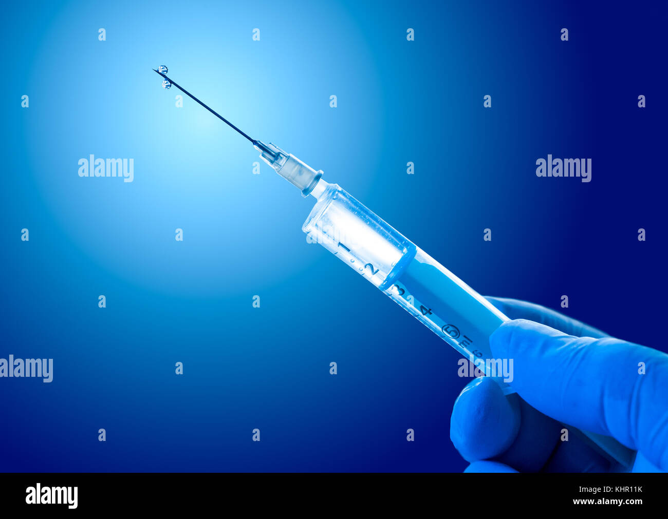 Syringe filled with vaccine on a blue background Stock Photo - Alamy