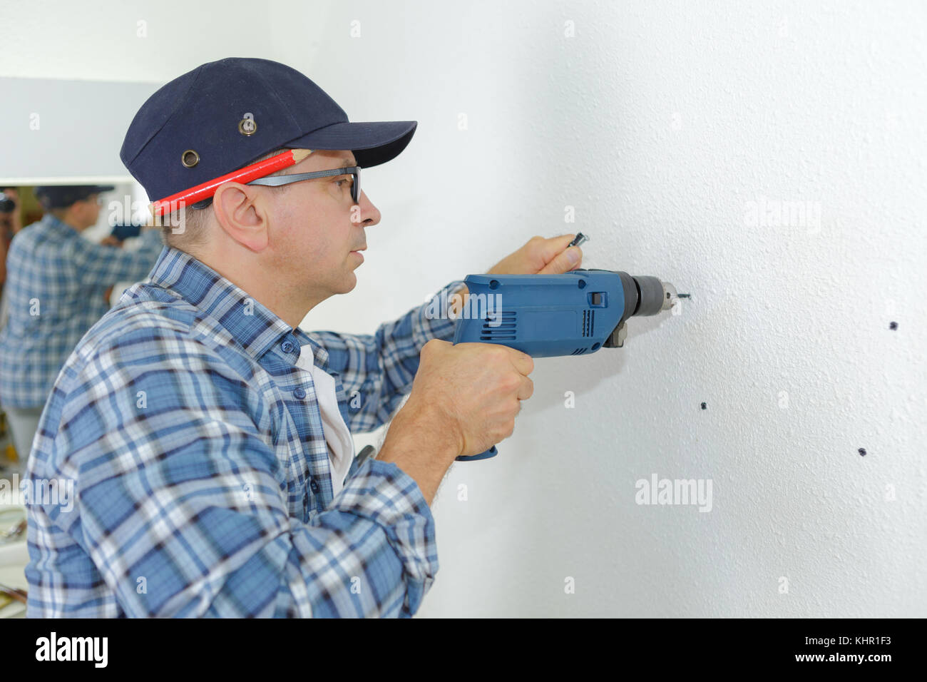 man drilling the wall with impact drill Stock Photo - Alamy