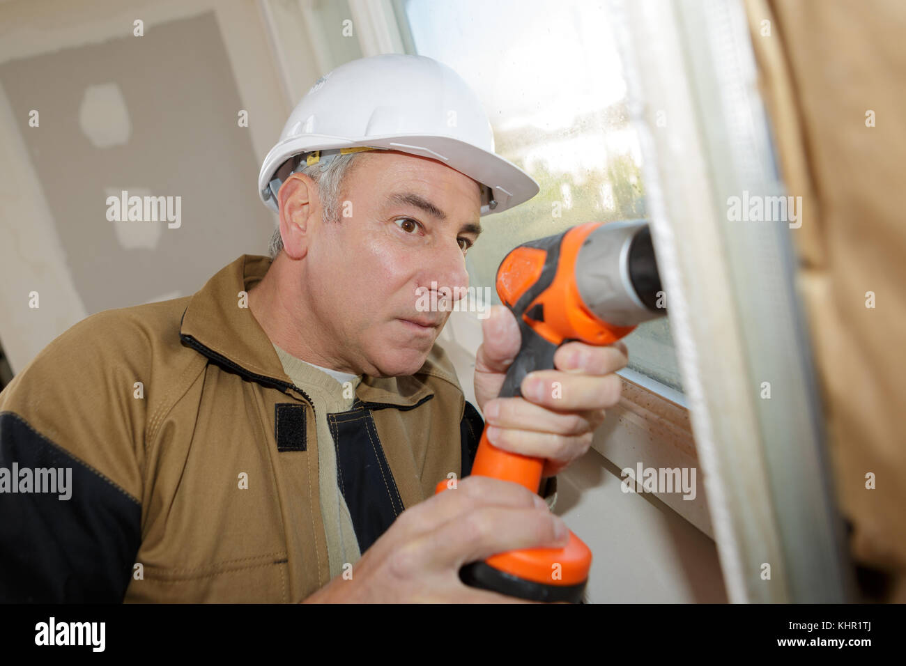 construction worker is drilling the wall with electric perforator Stock Photo