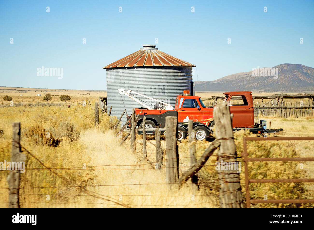 Two old tow trucks beside a silo in a field on a bright blue sky. Stock Photo