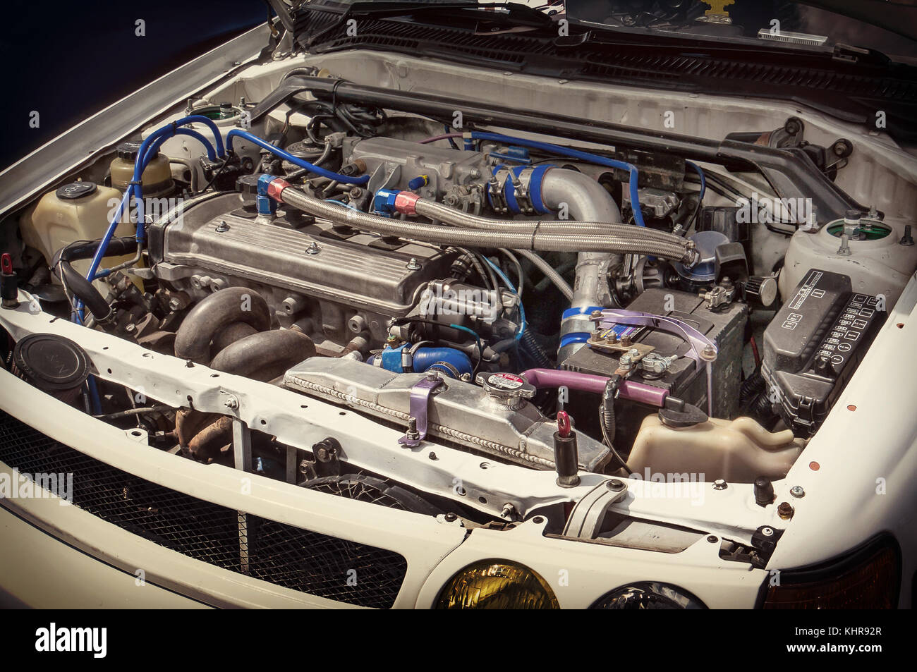 White car with open hood in auto repair shop. the motor is under the