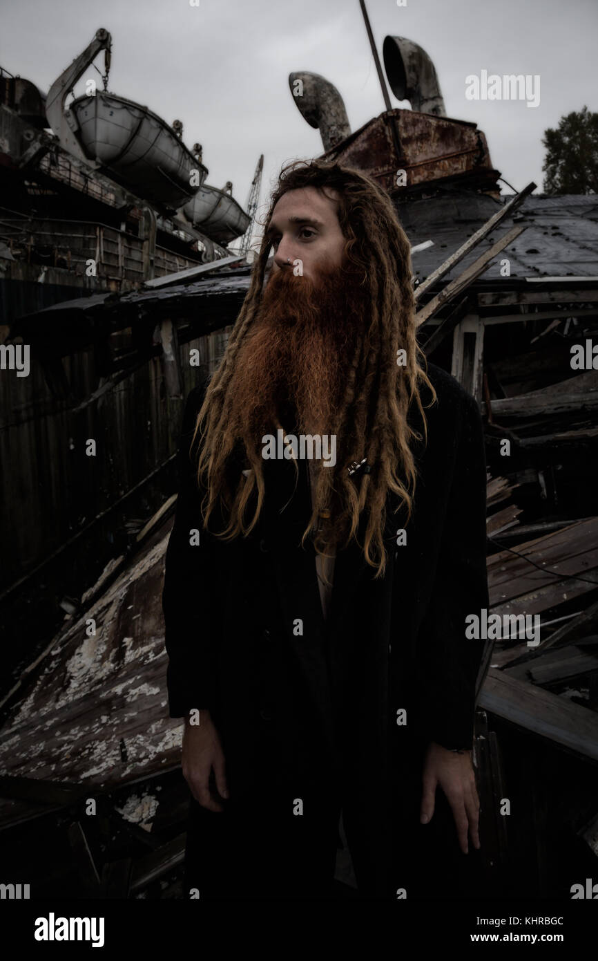 Striking dark mood portrait of a man with long beard and braided hair ...