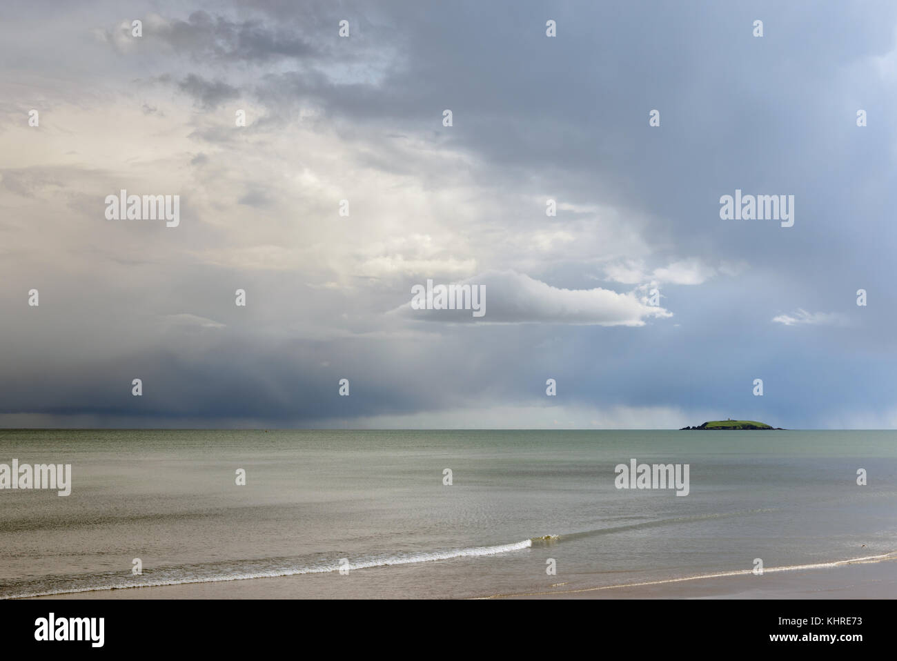 Capel island in Scottish Sea as seen from Youghal beach County Cork in Ireland on a dull day with calm waters and distant stormy skies Stock Photo