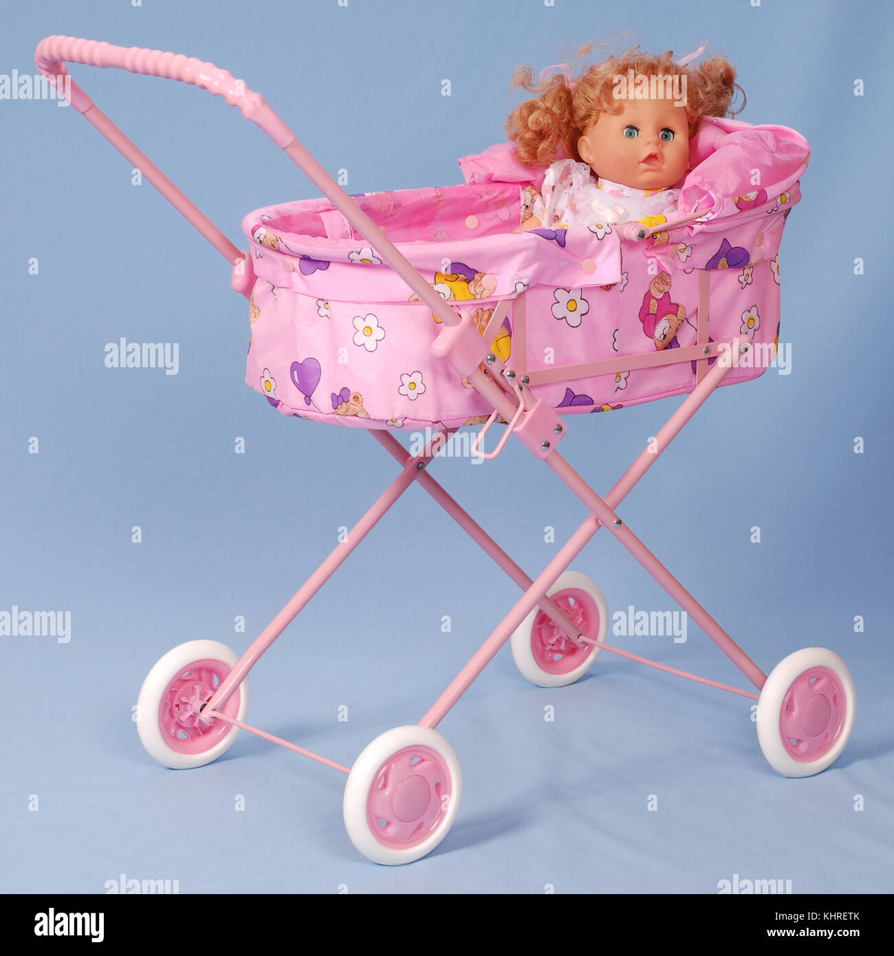 Toy baby buggy on blue background. On a carriage the doll lays. Stock Photo