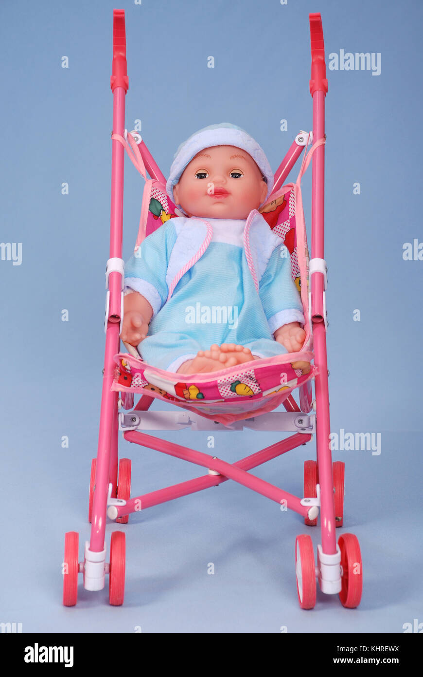 Toy baby buggy on blue background. On a carriage the doll lays. Stock Photo