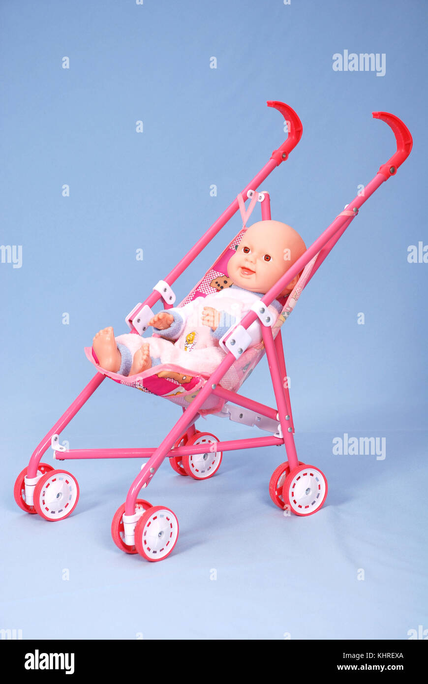 Toy baby buggy on blue background. On a carriage the doll lays. Stock Photo