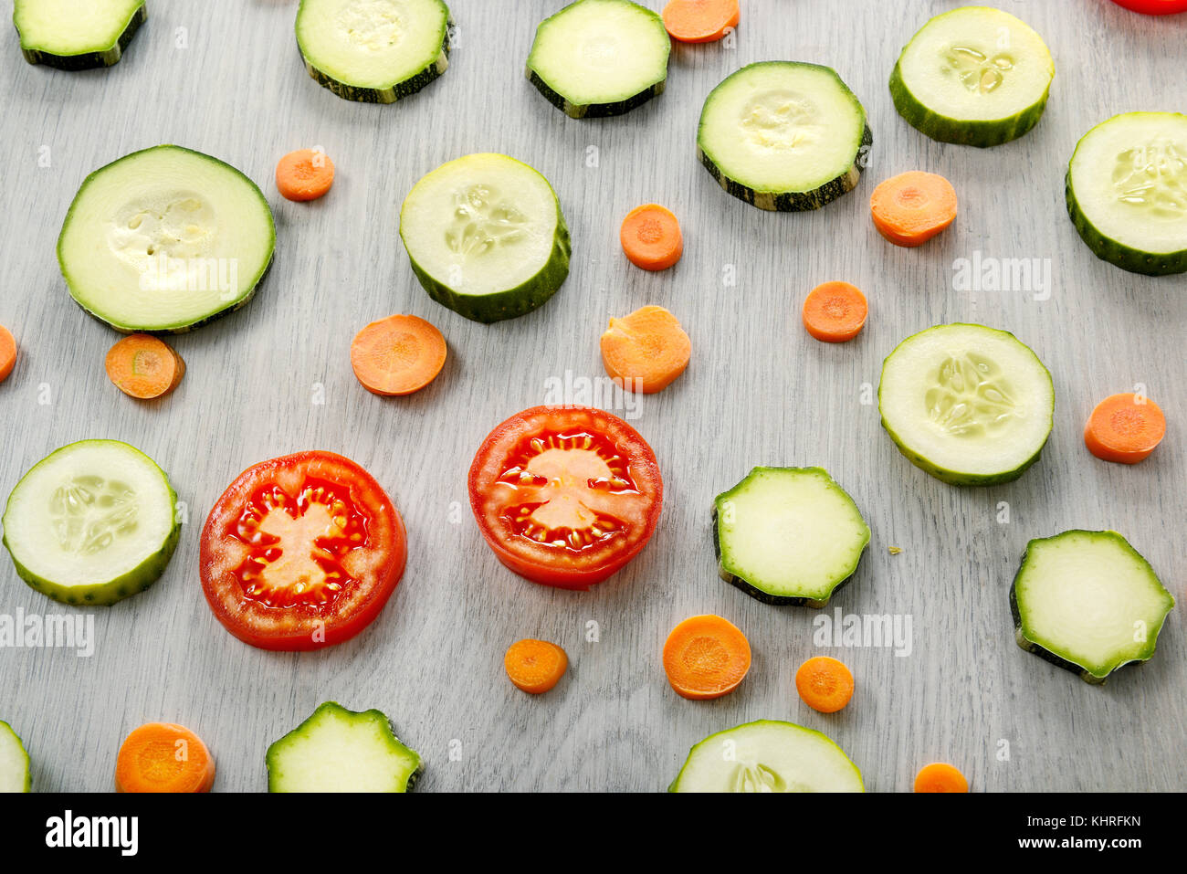 Background of healthy products on a wooden table. Top view of vegetables - zucchini, tomatoes, cucumbers, carrots. Stock Photo