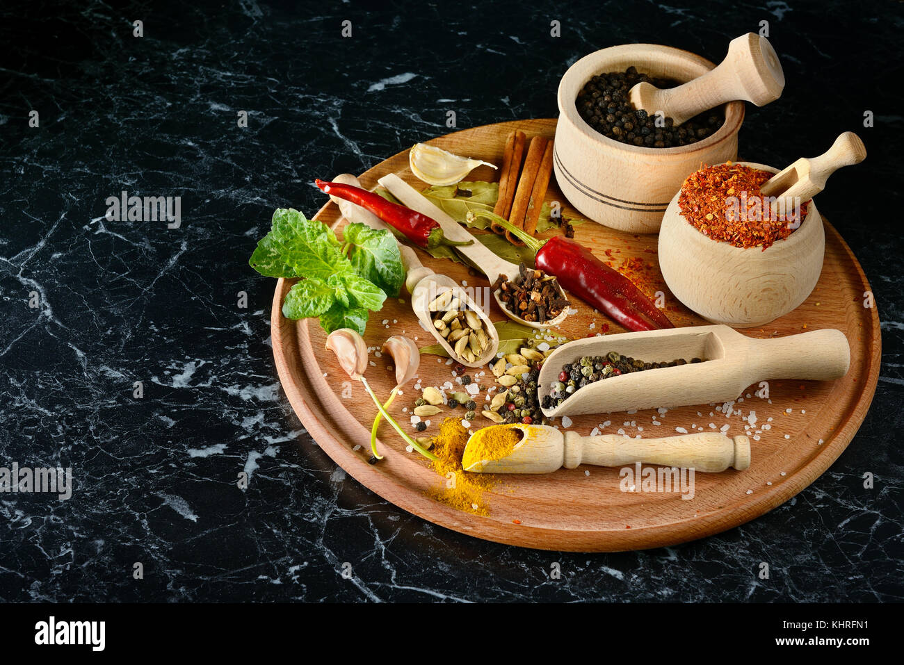 Variety spices in wooden spoons and cups on black background. Free space for text. Top view. Stock Photo