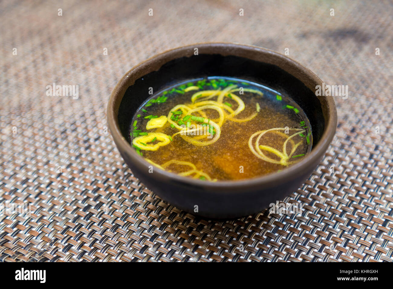 Miso soup in a brown ceramic bowl served on a table Stock Photo