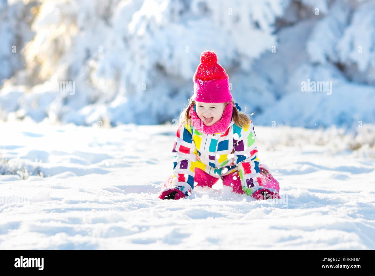 Child playing with snow in winter. Little girl in colorful jacket and ...