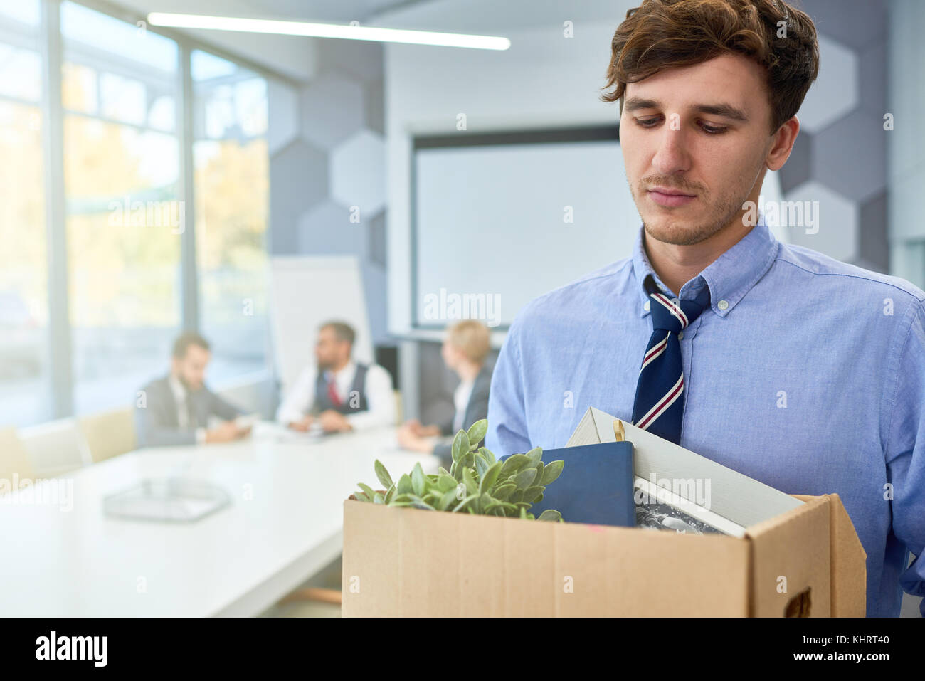 Portrait of sad young man holding box of personal belongings  fired from work in business company, copy space Stock Photo