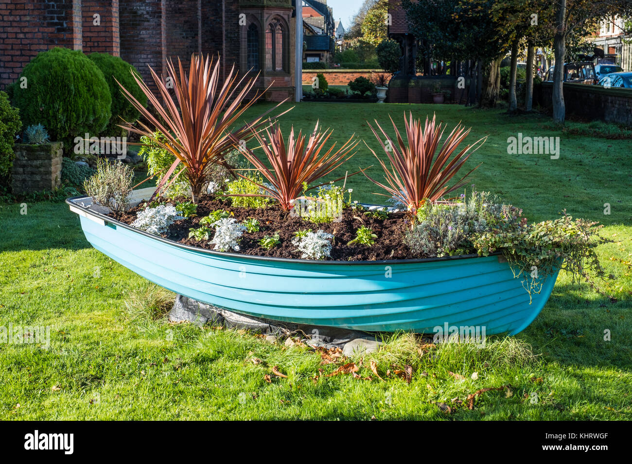 A lovely old rowing boat used as a planter and garden feature. Stock Photo