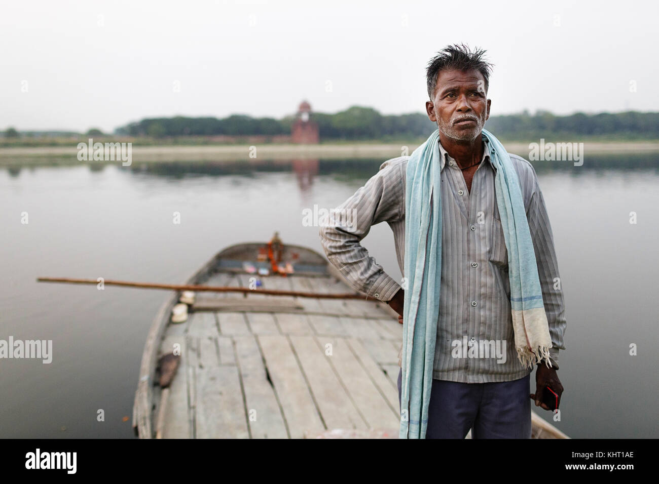 Indian fisherman with a scarf standing on his old traditional boat on Yamuna river at twilight, Agra, India. Stock Photo