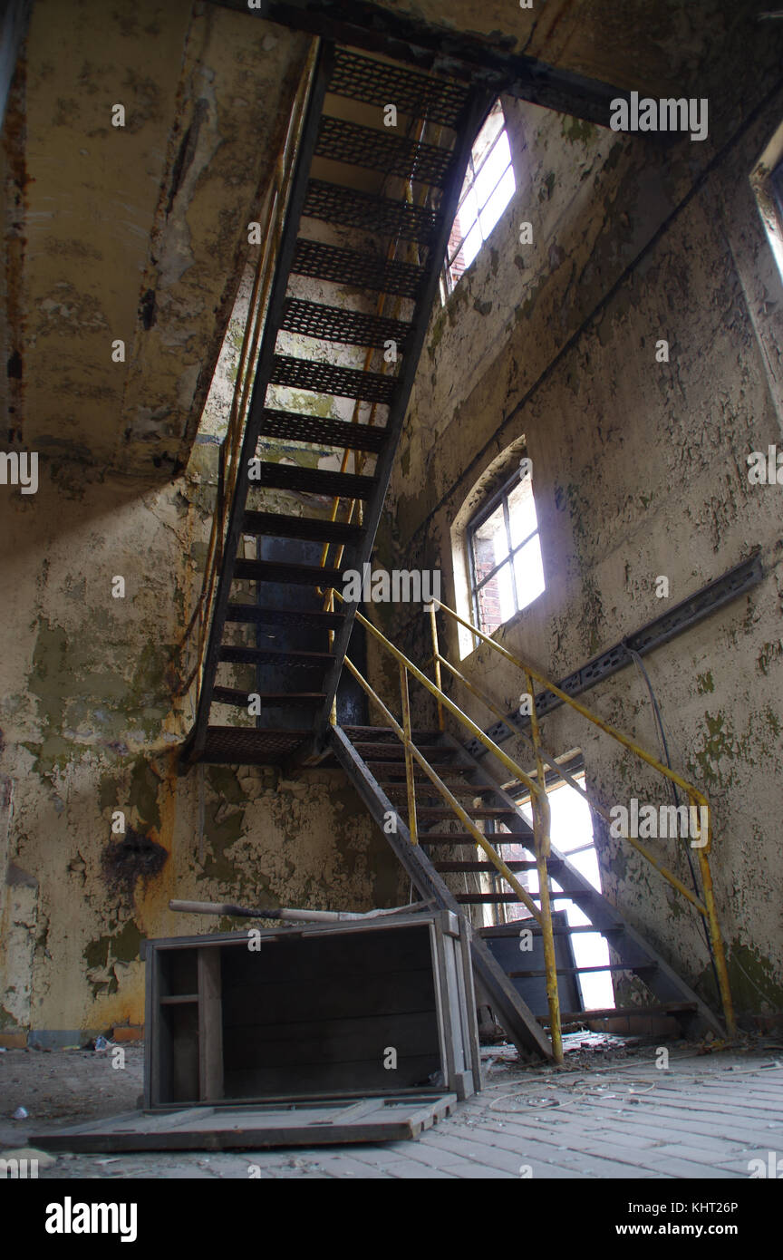 Stairs with yellow railing in a ruined industrial interior. Abandoned old factory. Stock Photo