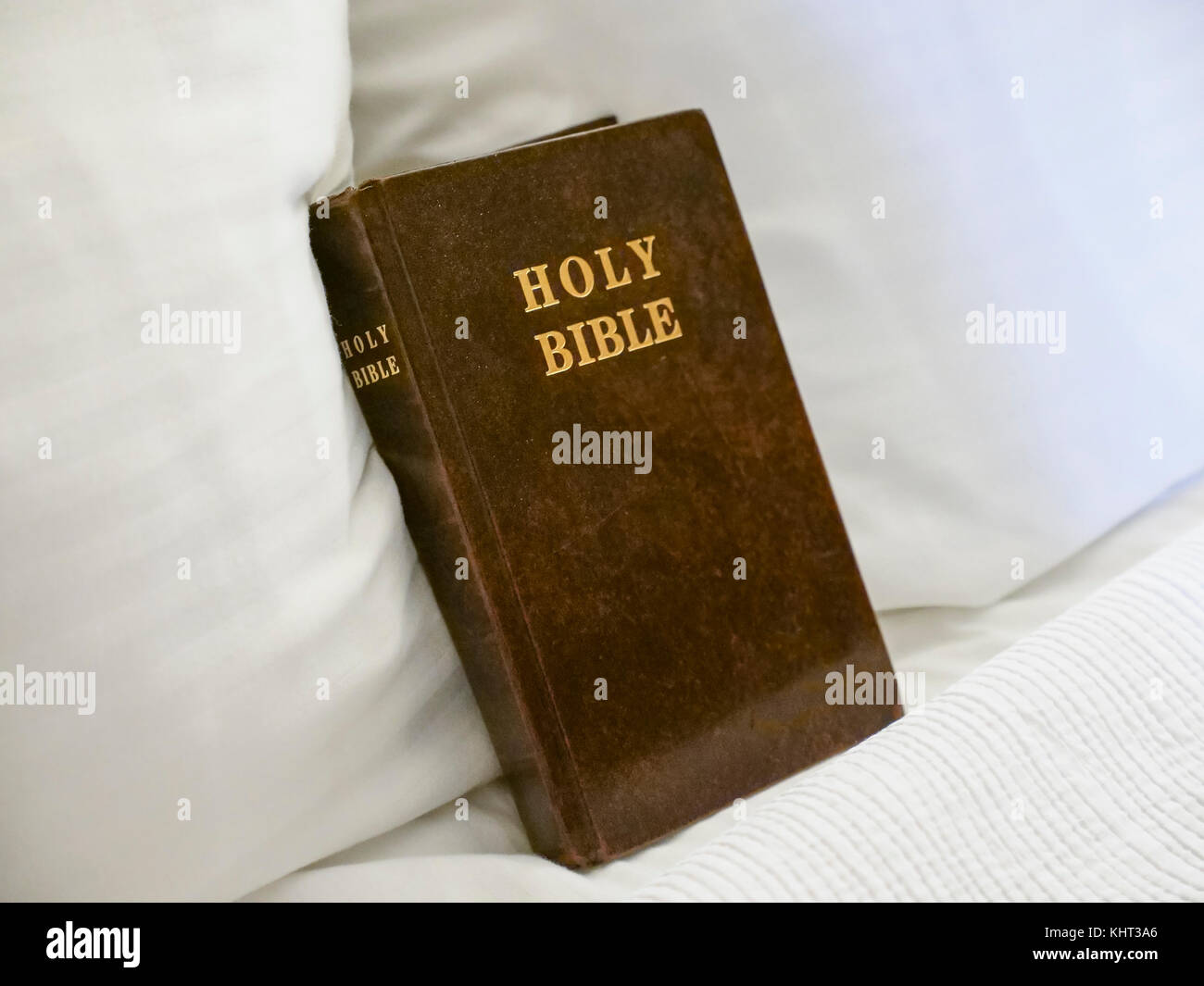 Holy Bible book placed on bed with white linen and inside hotel room