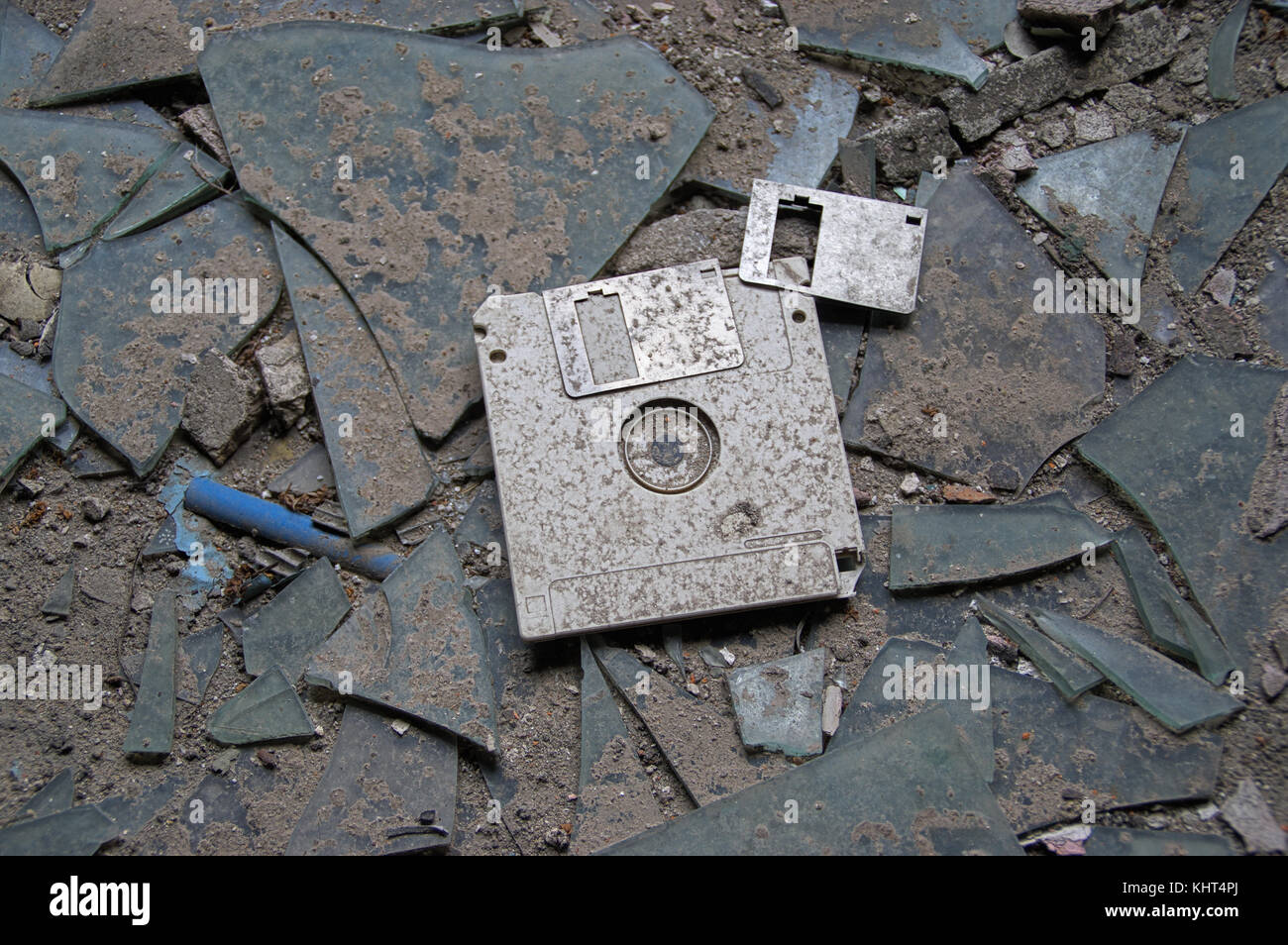 Destroyed and abandoned vintage floppy disc. Forgotten technologies - 3.5 inch disk in plastic case on broken glass. Stock Photo