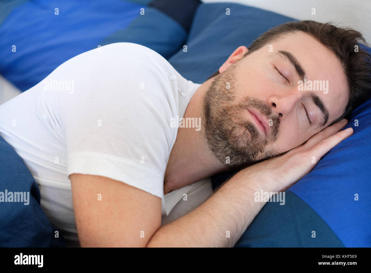 Tired man sleeping in bed under blankets Stock Photo Alamy