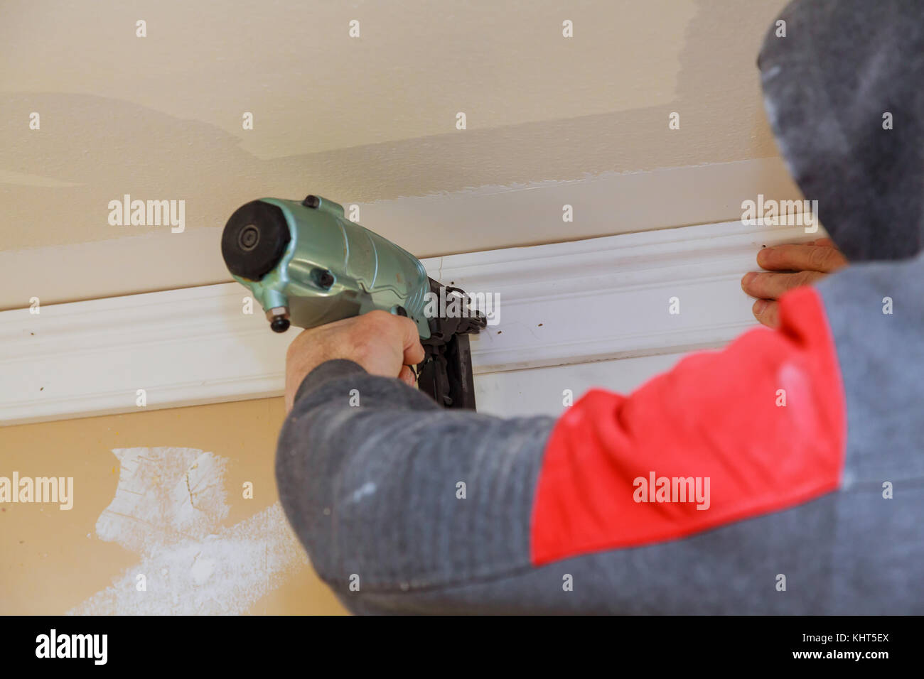 Carpenter brad using nail gun to Crown Moulding trim, warning label
