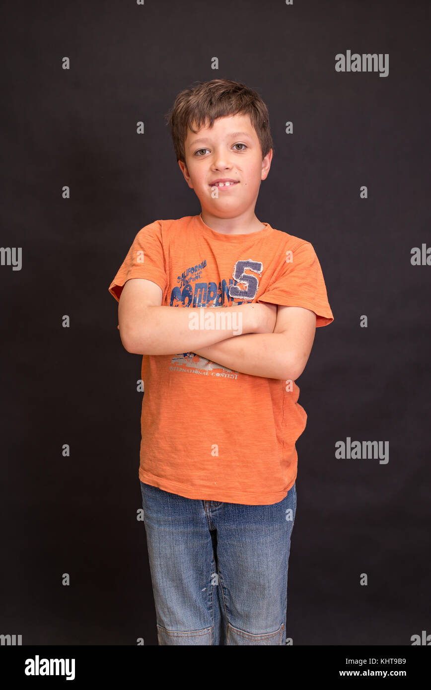A boy portrait, young little cute and adorable kid, little obstreperous scamp. Poses, face expressions, ease, having fun, black background. Stock Photo