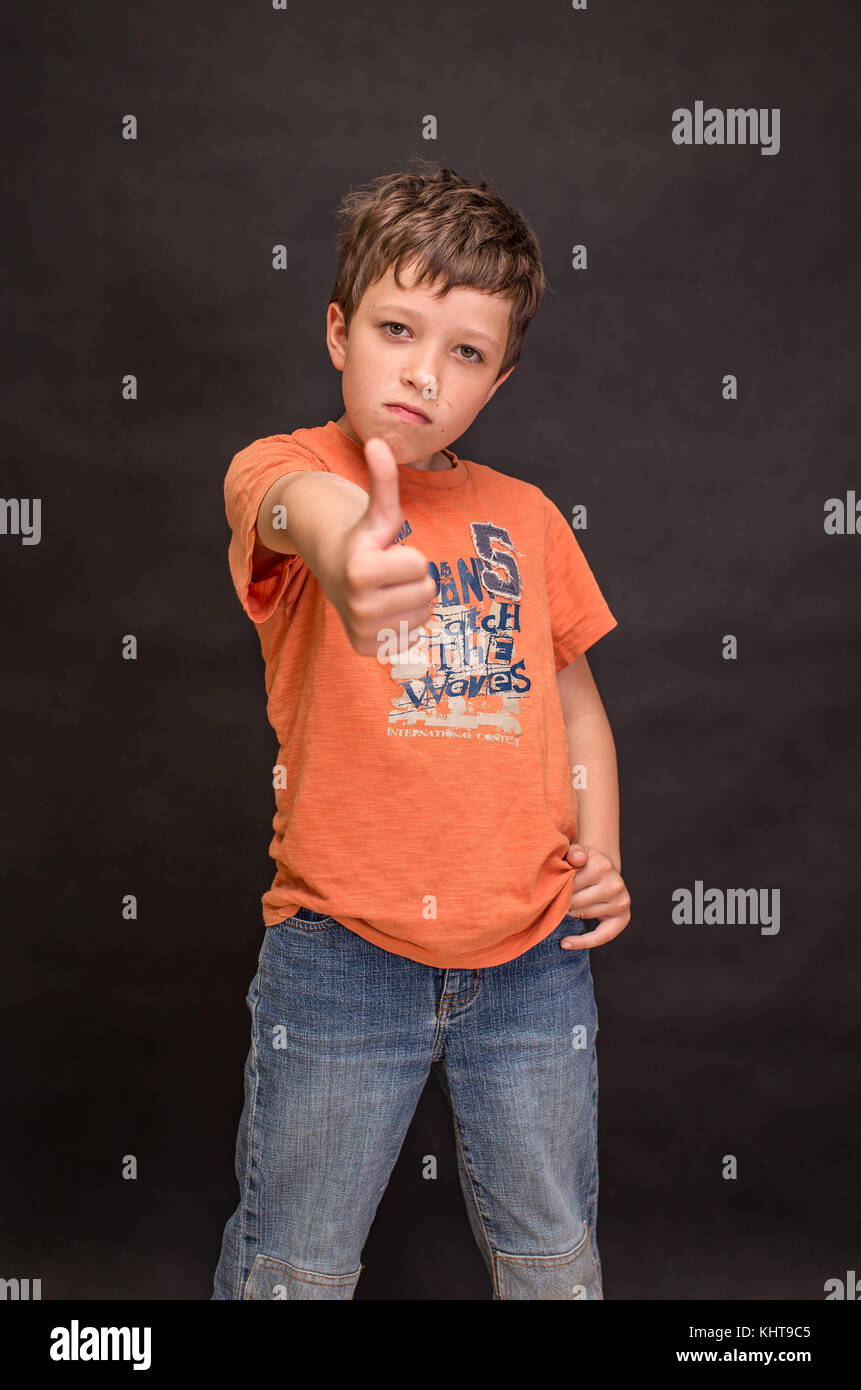 A boy portrait, young little cute and adorable kid, little obstreperous scamp. Poses, face expressions, ease, having fun, black background. Stock Photo